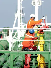 Two crew members working on a tanker's deck manifold